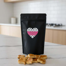 Load image into Gallery viewer, Vegemite Oat Dog Cookies bag with heart-shaped treats on a kitchen counter.