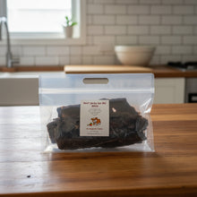 Load image into Gallery viewer, A clear plastic bag containing dark beef jerky pieces, with a white label reading 'Beef Jerky for BIG DOGS' and a small cartoon dog logo, placed on a kitchen bench