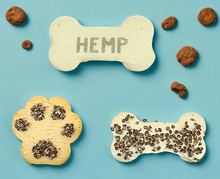 Load image into Gallery viewer, HEMP COOKIES shaped like dog bones and paw prints, featuring hemp seeds and vegan ingredients on a blue background.
