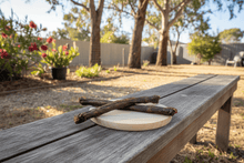 Load image into Gallery viewer, Two dried X-Large Aussie Roo tails high protein on a wooden bench in an Australian back yard