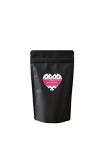 Load image into Gallery viewer, Packaging of banana oat dog cookies in a black pouch with a heart design on a wooden table.