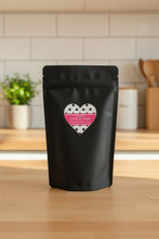 Load image into Gallery viewer, Black pouch with a heart-shaped label featuring polka dots and text on a beige background