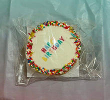 Load image into Gallery viewer, Small round cake with 'Happy Birthday' sprinkles on a clear plastic bag against a light blue background.
