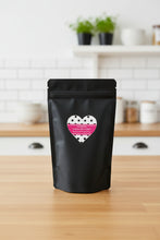 Load image into Gallery viewer, Black packaging with a heart-shaped label on a beige background
